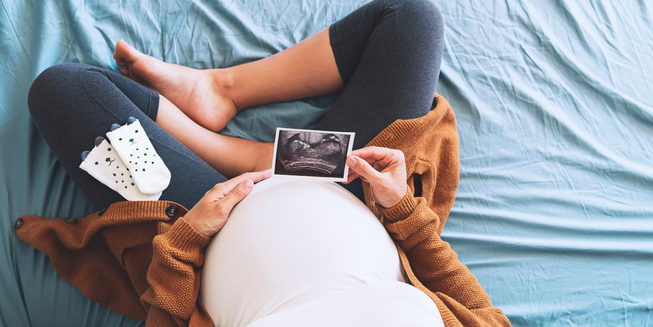 A pregnant woman in her third trimester admires an ultrasound picture.